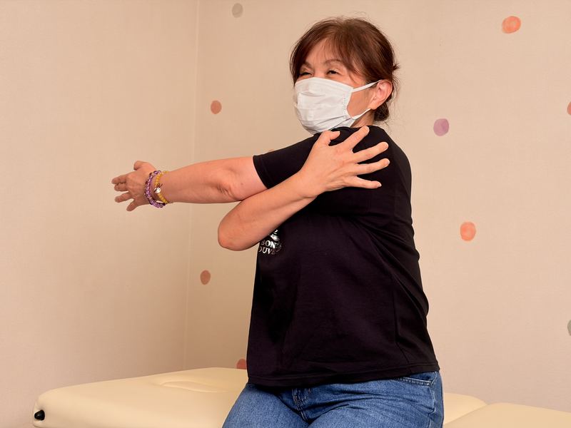 腕を胸の前で抱えて肩のストレッチをするお客様