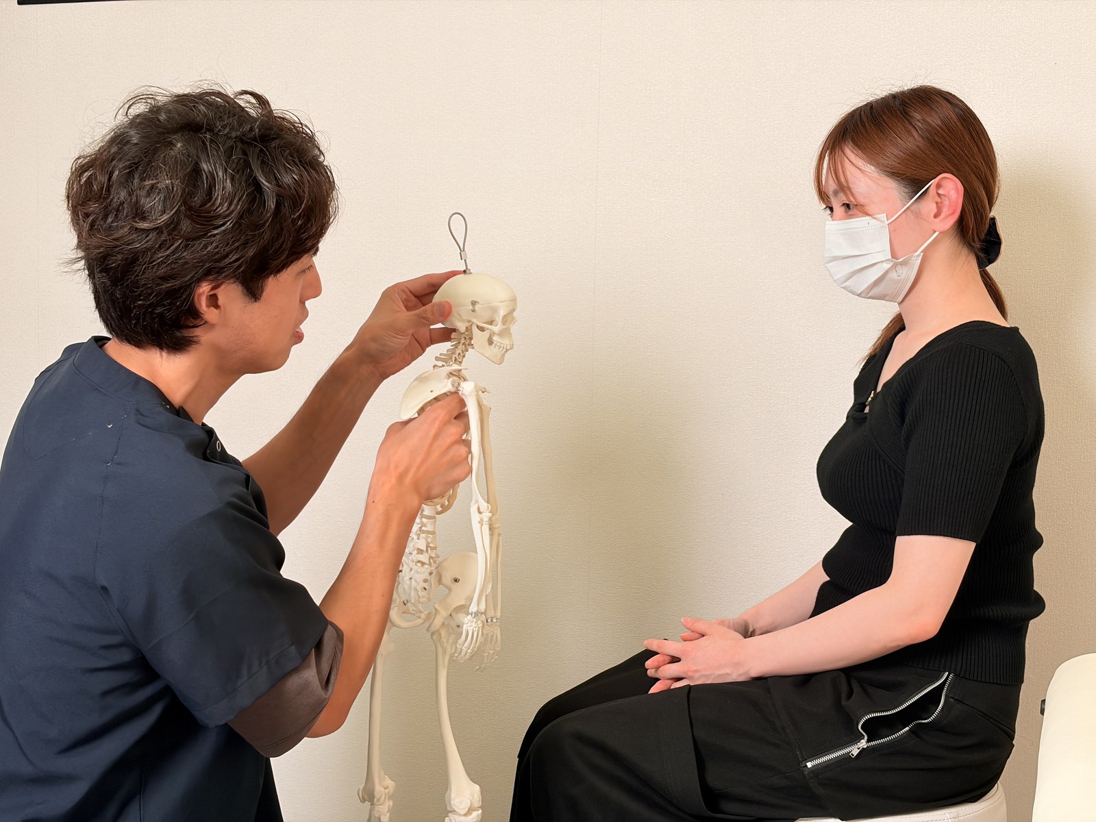 背骨の模型を見せながら、今の姿勢の状態を説明する院長
