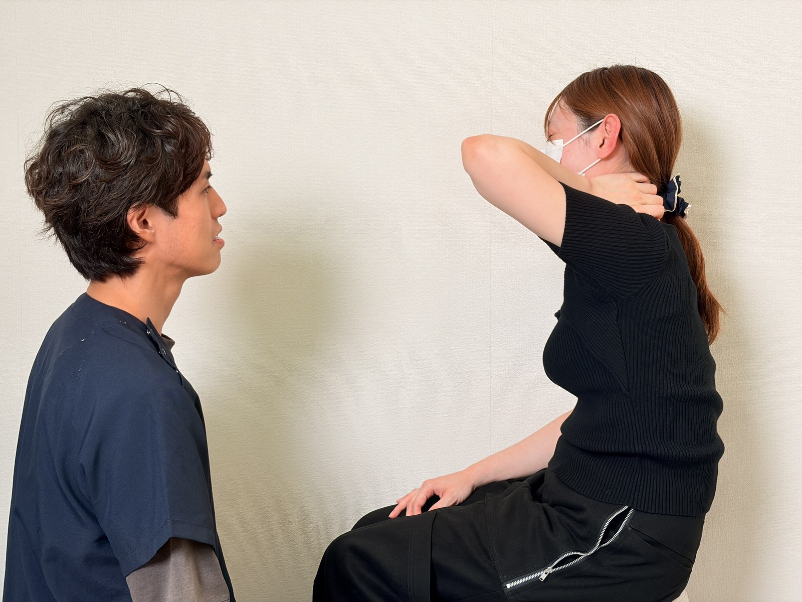 首の後ろに手を当てて痛む場所を伝える方と、向かい合って聞く院長
